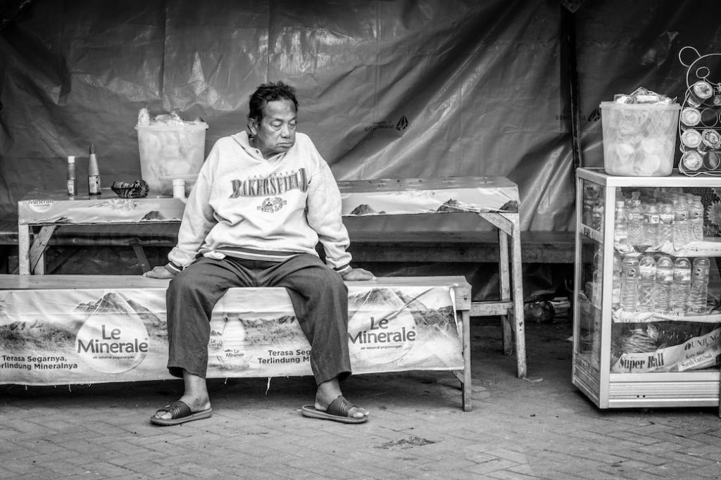 grayscale photography of man sitting on bench