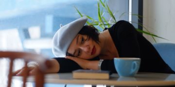 woman in black long sleeve shirt lying on white wooden table