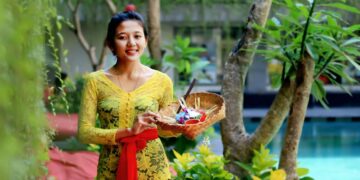 woman in yellow floral dress holding clear glass bowl with fruits