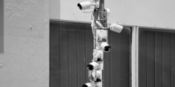a black and white photo of security cameras on a pole