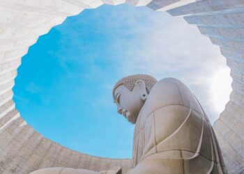 a large buddha statue sitting under a blue sky