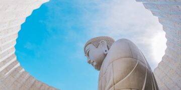 a large buddha statue sitting under a blue sky