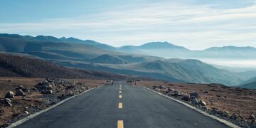 an empty road with mountains in the background