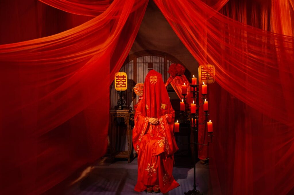 Vibrant red traditional wedding scene with bride in veil and candles.
