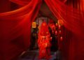 Vibrant red traditional wedding scene with bride in veil and candles.