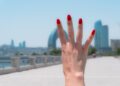 Hand with red nails showing four fingers