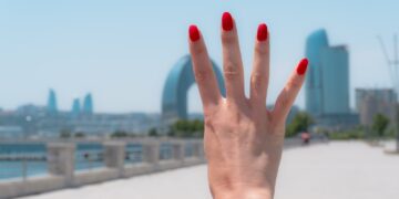 Hand with red nails showing four fingers