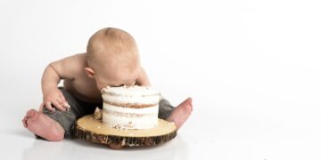 kid sitting beside round cake close-up photography