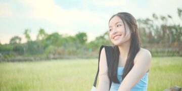 a woman in a blue dress sitting in a field